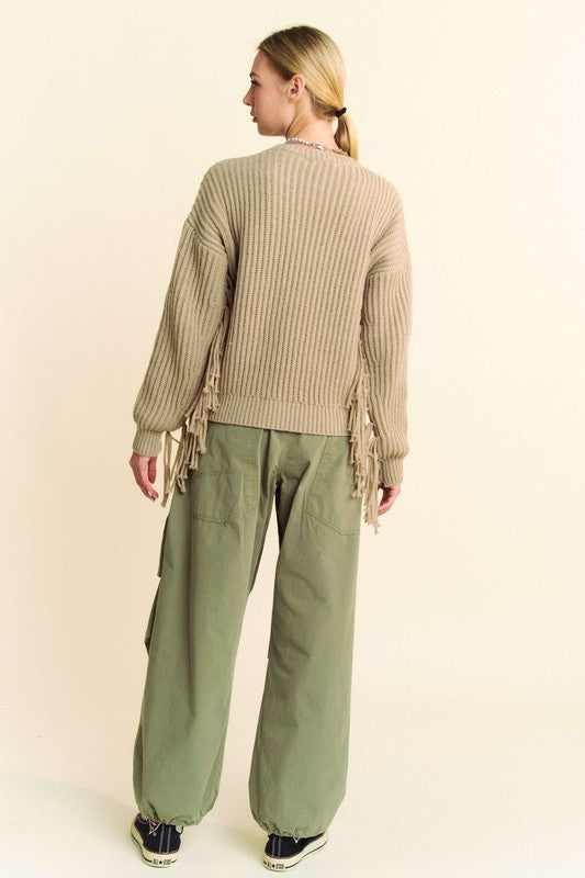 Back view of a model wearing Davi & Dani drawstring baggy pants with pockets in olive green, styled with a beige fringe sweater.