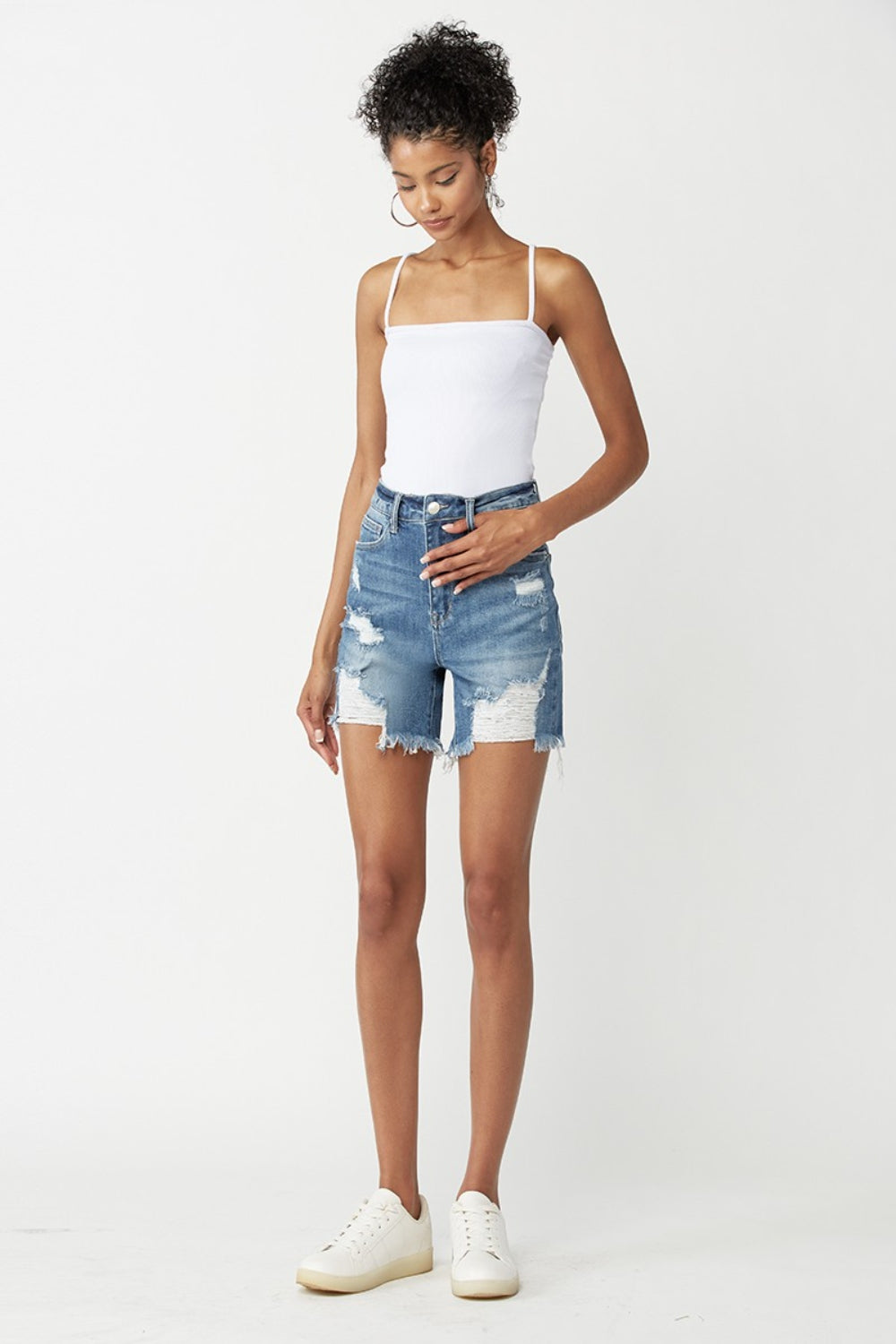 Model wearing RISEN High Waisted Distressed Denim Shorts paired with a white tank top and sneakers for a stylish summer outfit.