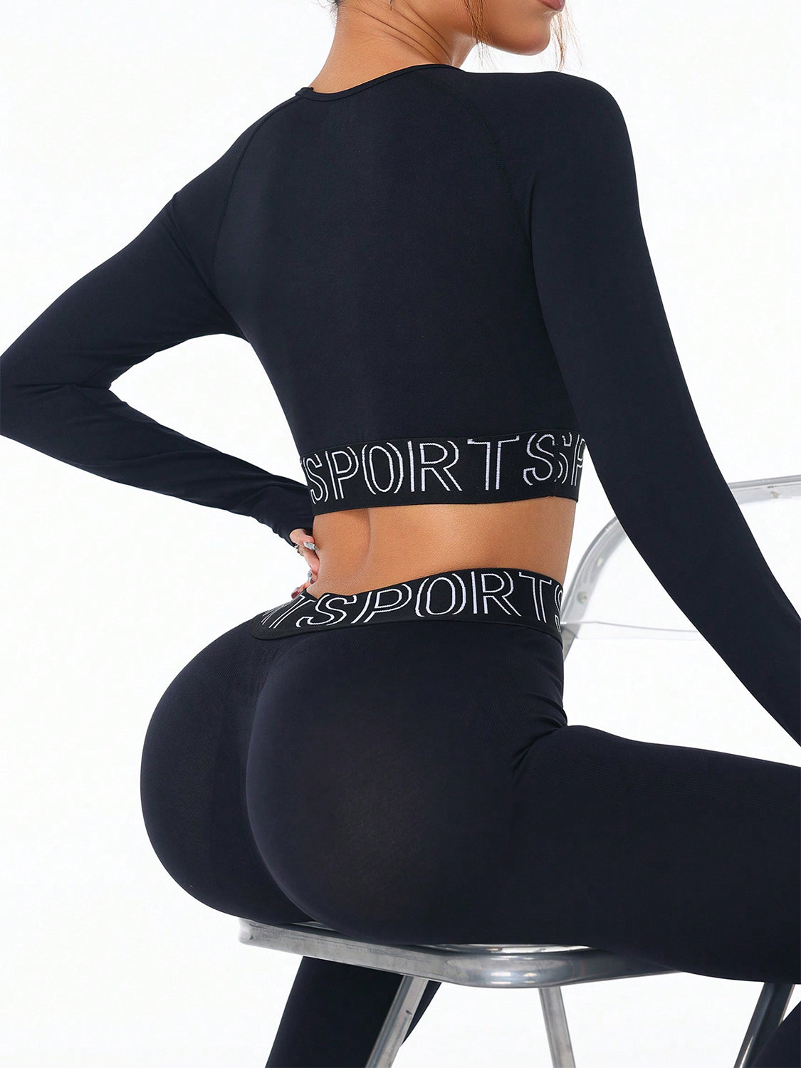 Close-up of black letter print activewear set featuring a round neck long sleeve crop top and high-waisted leggings with elastic waistband.