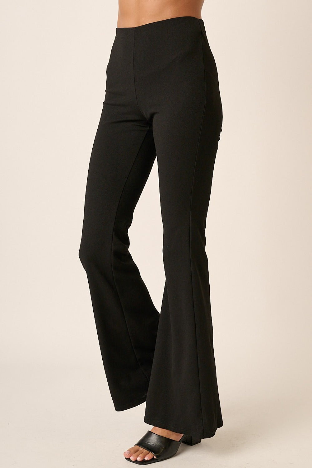 Side angle of Mittoshop Crepe Knit Elastic Waist Flare Leg Pants in black, highlighting the sleek silhouette and flared hem.