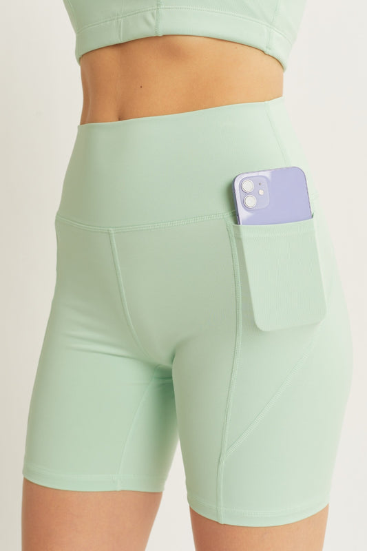 Love Tree High Waist Seam Detail Active Shorts in mint green with a side pocket holding a smartphone, showcasing a sleek and functional design.