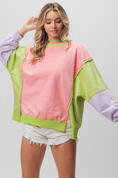 BiBi Washed Color Block Sweatshirt with pink, green, and lavender panels, featuring a relaxed fit and raw edge details. Styled with white denim shorts.