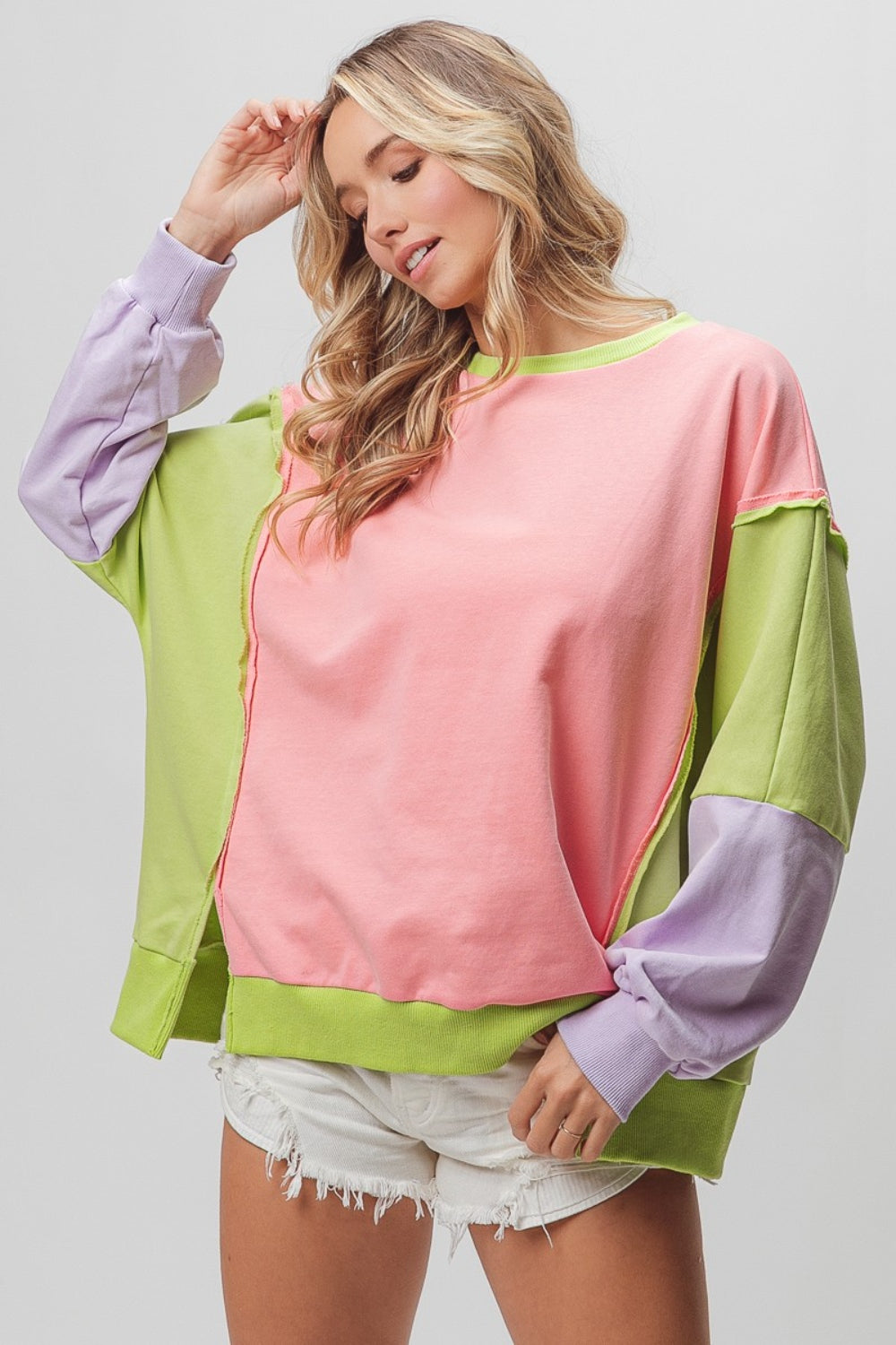 BiBi Washed Color Block Sweatshirt in pink, green, and lavender tones, styled with white shorts. Features raw edges and a trendy oversized fit.