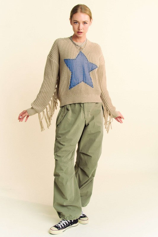 Full front view of Davi & Dani drawstring baggy pants with pockets in olive green, styled with a beige sweater featuring a blue star design.